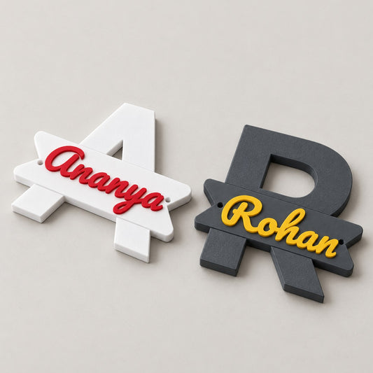 Initial Name Plaque: white A Ananya and grey R Rohan plaques lying flat side by side, top-down at a slight angle