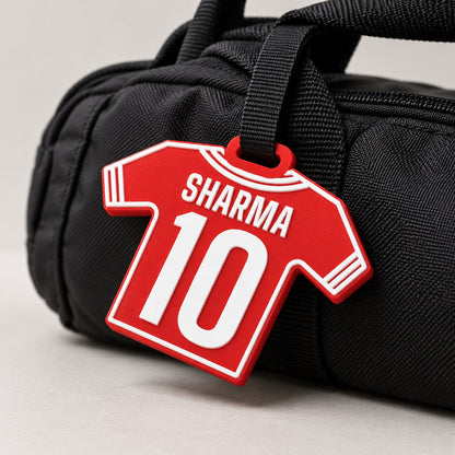 Jersey Kit Bag Tag: red 'SHARMA 10' tag hanging by a black strap from the handle of a black sports kit bag