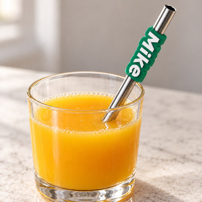 Name Tag for Pen or Straw: 'Mike' tag slid onto a reusable steel straw in a glass of juice, on a light table