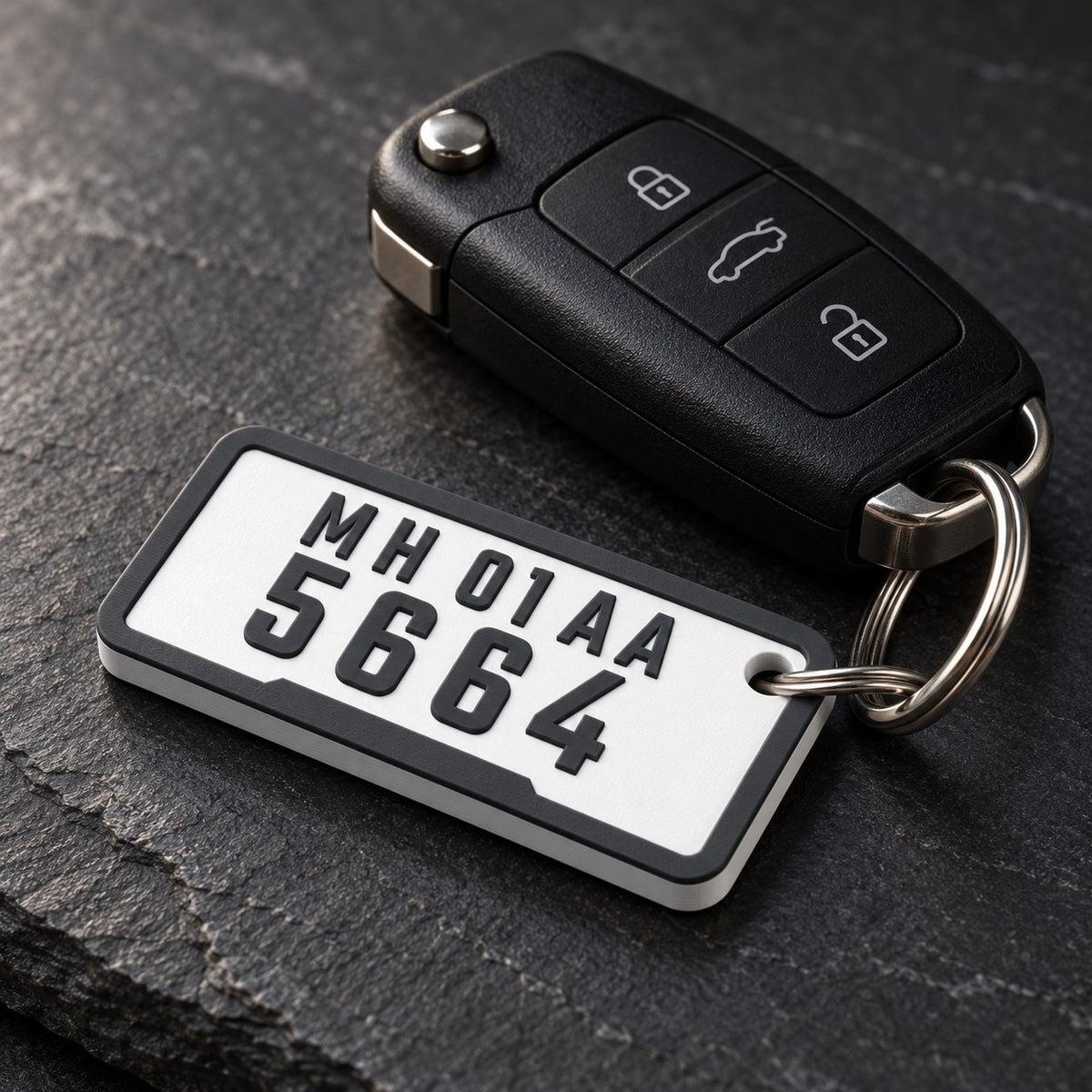 Number Plate Keychain: 'MH 01 AA 5664' keychain on a steel split ring next to a black car key fob on a dark slate surface