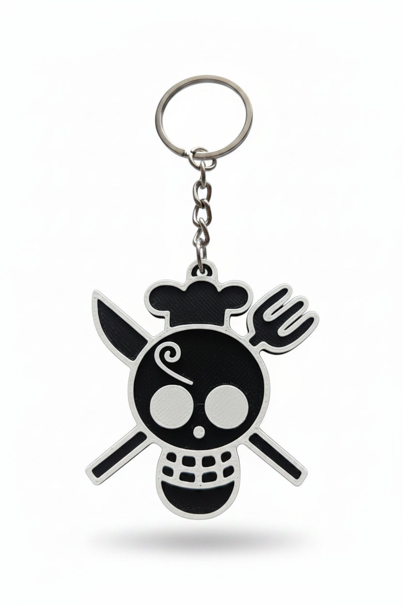 A 3D-printed keychain featuring a stylized skull and crossbones design in black and white, attached to a silver metal split ring and chain, set against a plain light background.
