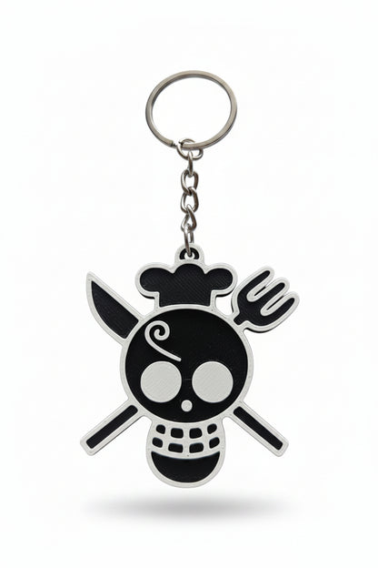 A 3D-printed keychain featuring a stylized skull and crossbones design in black and white, attached to a silver metal split ring and chain, set against a plain light background.
