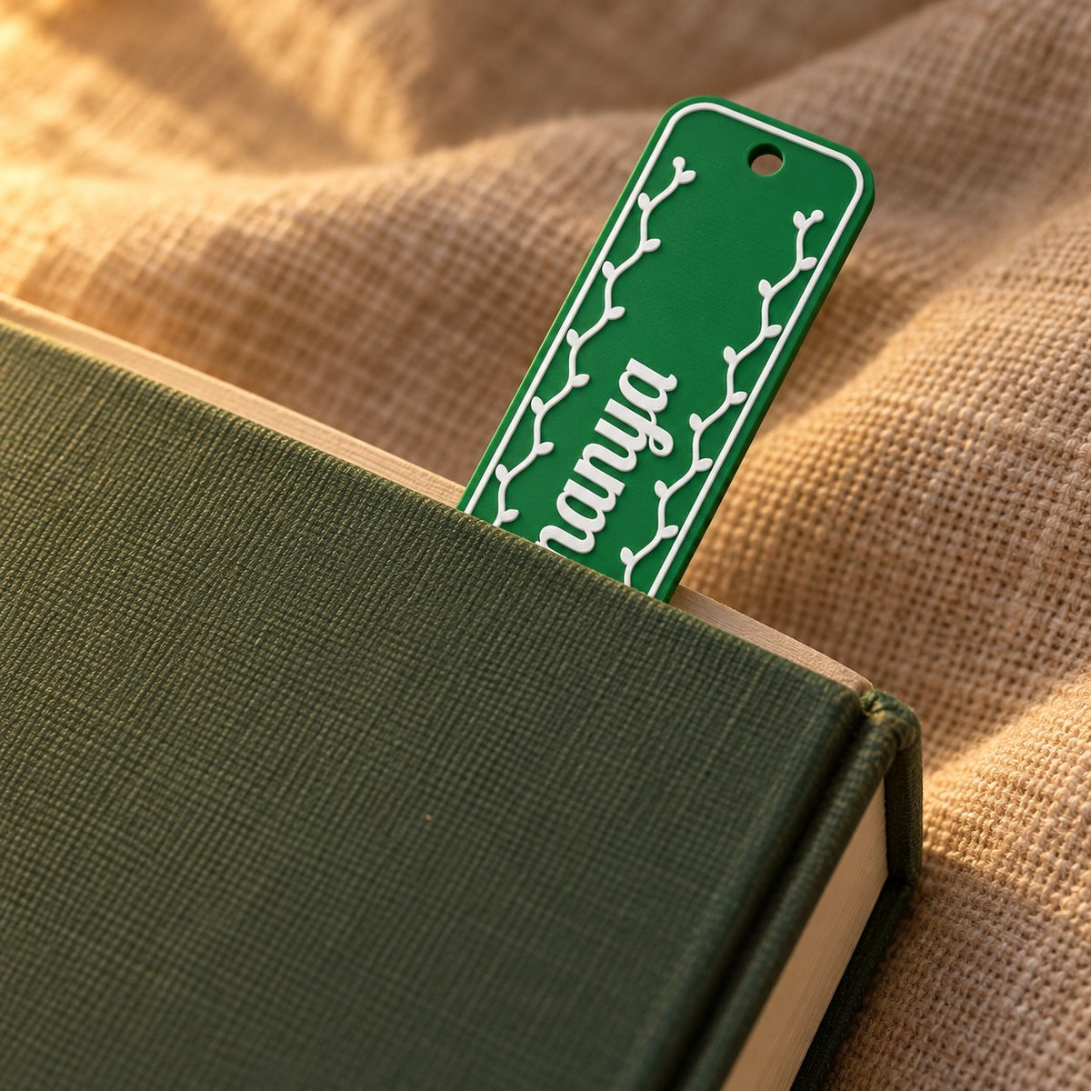 Name Bookmark: green 'Ananya' bookmark tucked into a closed hardback book on a linen throw, its top end showing above the pages