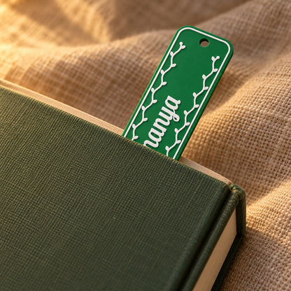 Name Bookmark: green 'Ananya' bookmark tucked into a closed hardback book on a linen throw, its top end showing above the pages