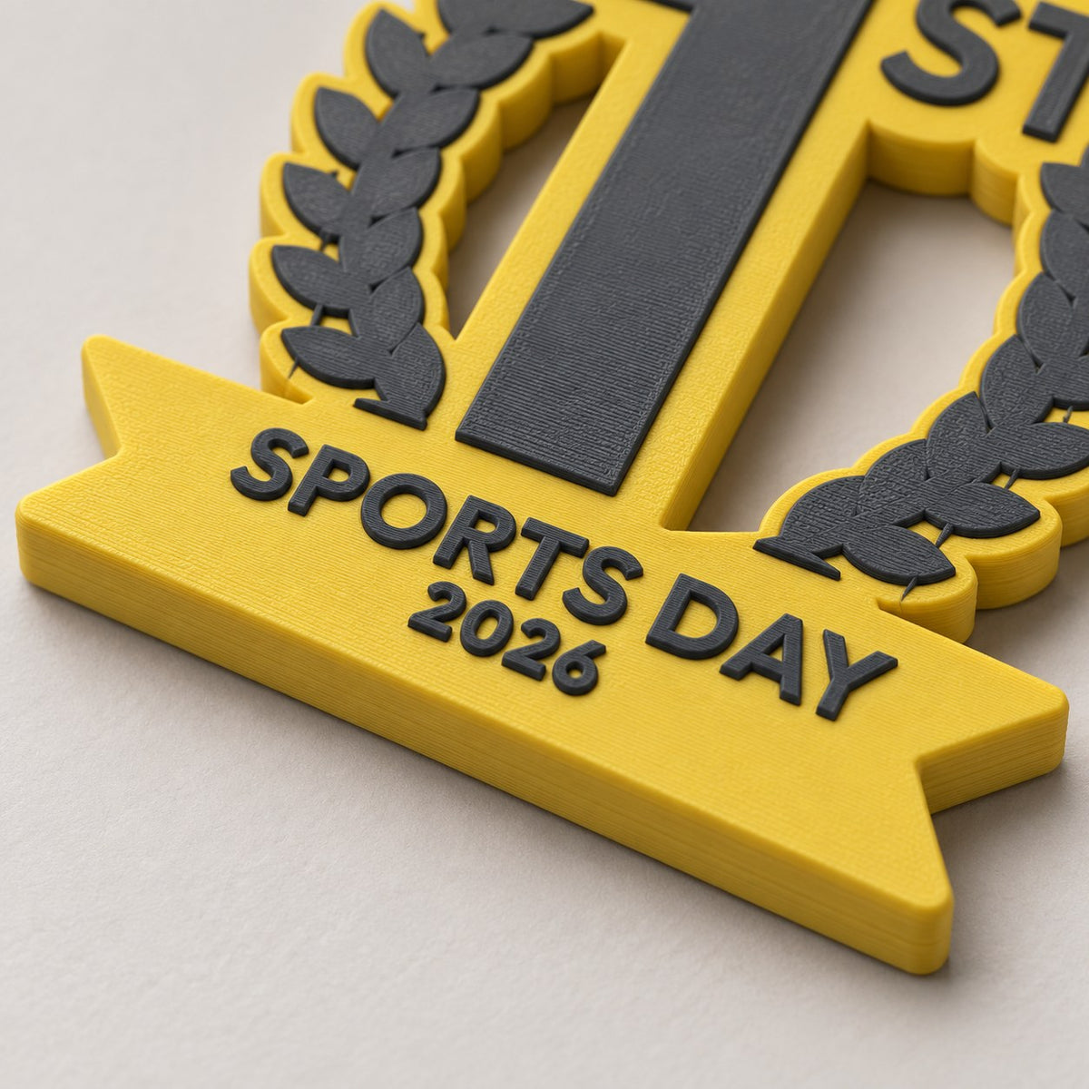 Close-up of the laurel and Sports Day 2026 banner on a yellow podium medal