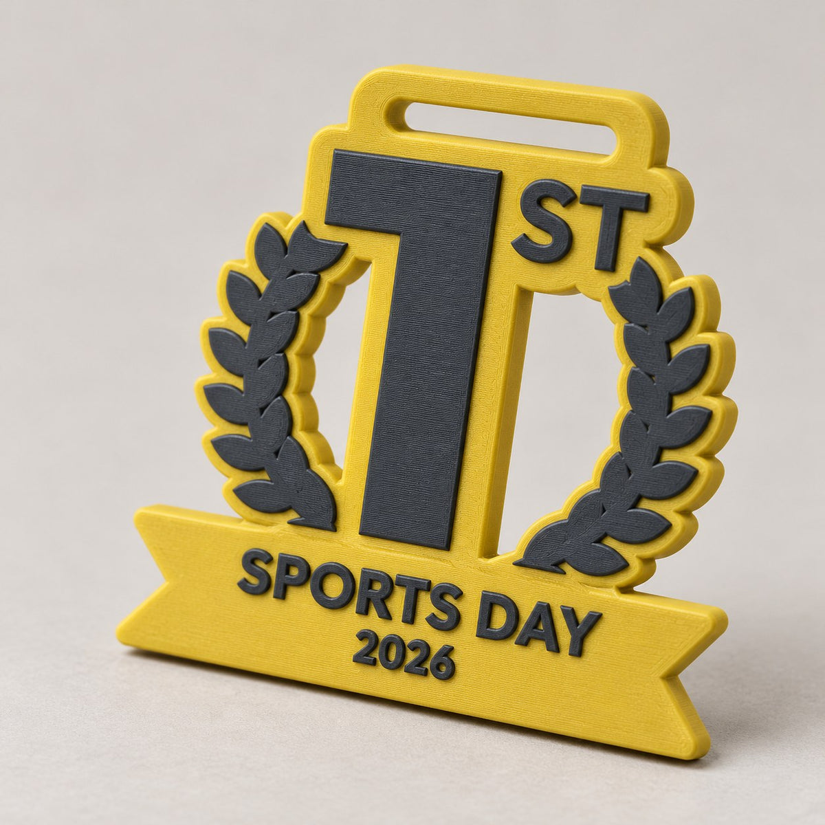 Yellow 3D-printed podium medal shaped like a 1 with ST, a laurel wreath and a Sports Day 2026 banner
