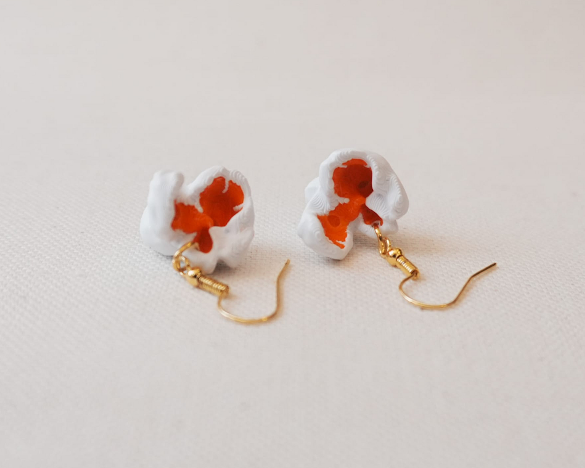 Pair of earrings with a white base and red floral design on a light background, branded 'Eyf_design'.
