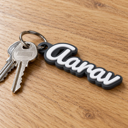 Personalised Name Keychain: 'Aarav' keychain on a steel split ring with two house keys, lying on a light oak table, natural window light