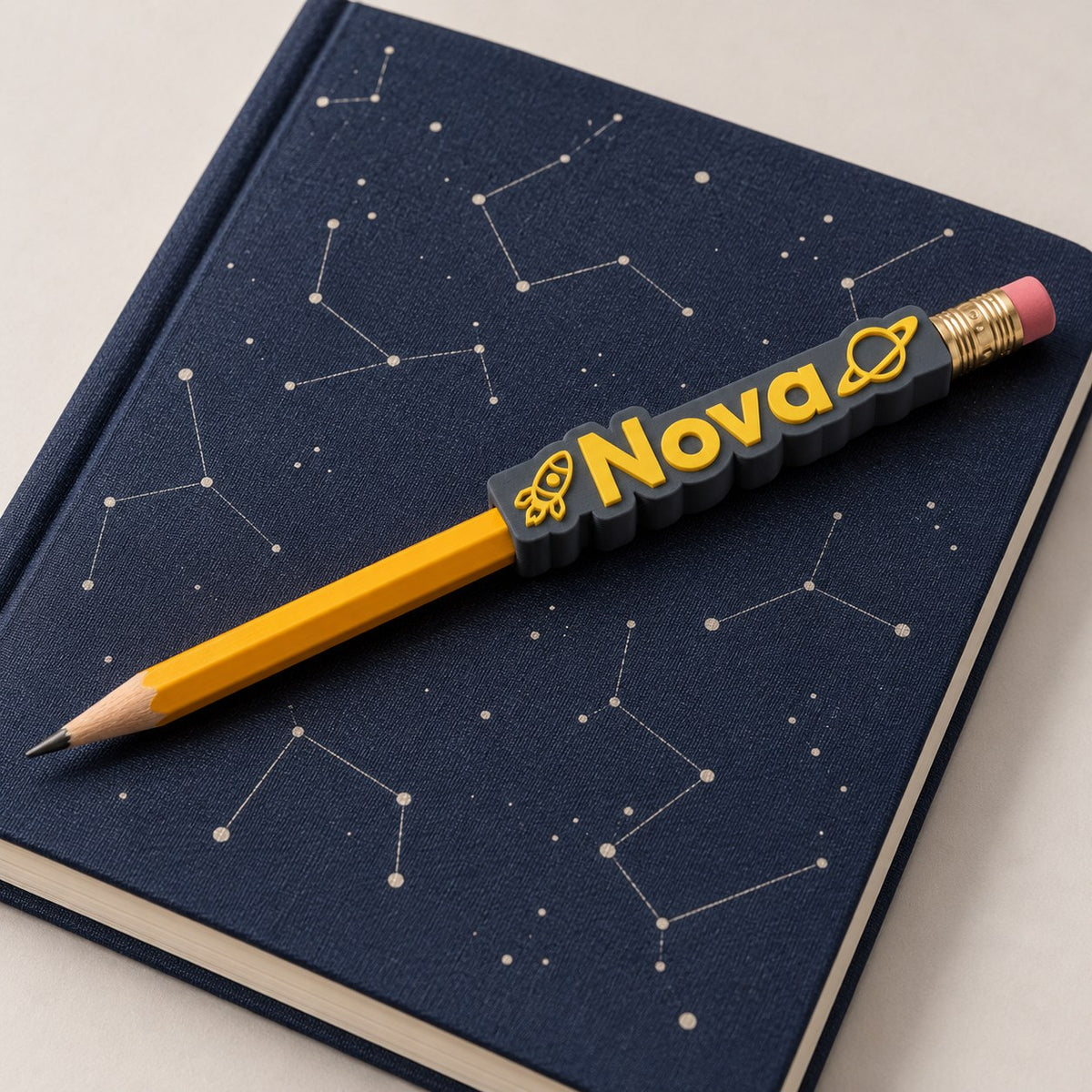 Space Name Pencil Topper: 'Nova' topper on a pencil lying on a navy star-chart notebook