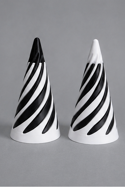 Three small cone-shaped decorative objects with black-and-white diagonal stripes are shown on a gray studio background, with one larger view above and two smaller views below.