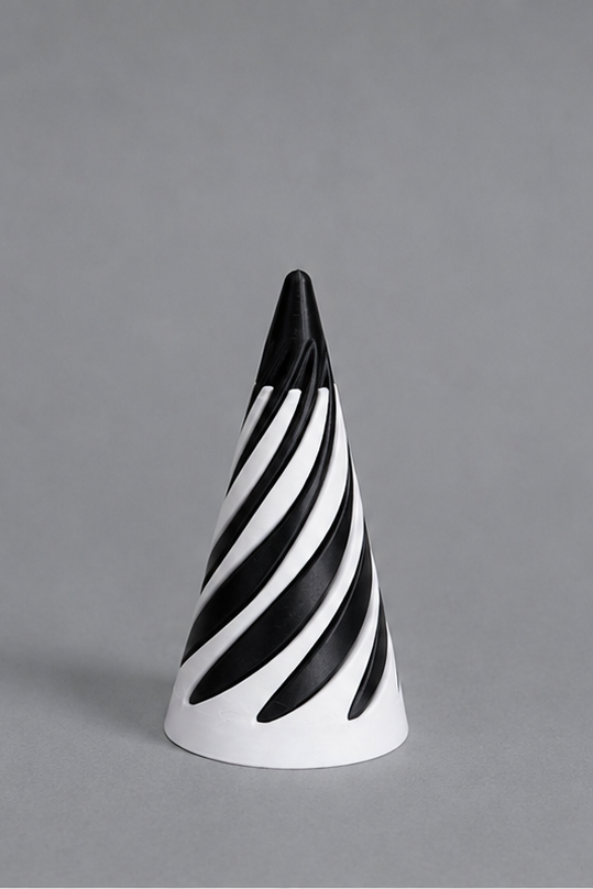 A modern cone-shaped decorative object featuring a bold black and white spiral stripe pattern, photographed against a solid gray studio background.