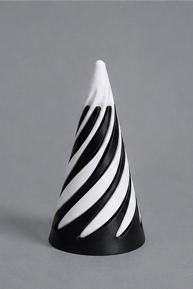 A cone-shaped decorative object with a black and white spiral stripe pattern, standing upright on a neutral gray background.