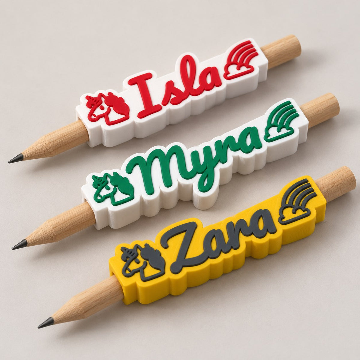 Unicorn Name Pencil Topper: three toppers (Isla, Myra, Zara) each on the top of a pencil, the pencils lying side by side
